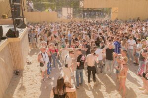 Large gathering enjoying a sunny outdoor music festival by the beach. Perfect summer vibes.