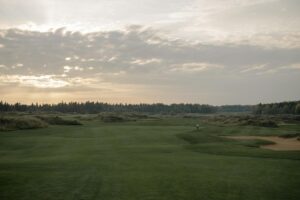 Expansive twilight view of a tranquil golf course with lush greenery under a dramatic sky.