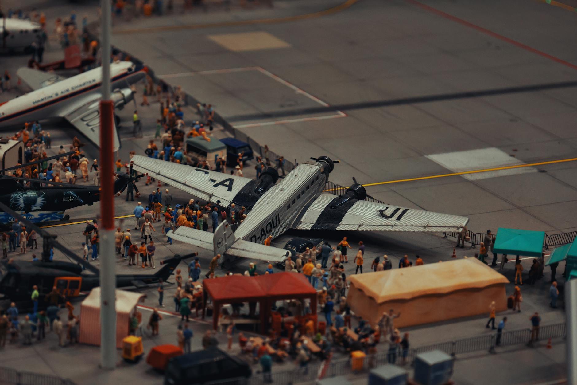 A detailed miniature scene of airplanes and people at a crowded airport display.