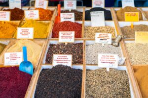 Close-up of a vibrant spice display in a market with labels in multiple languages.
