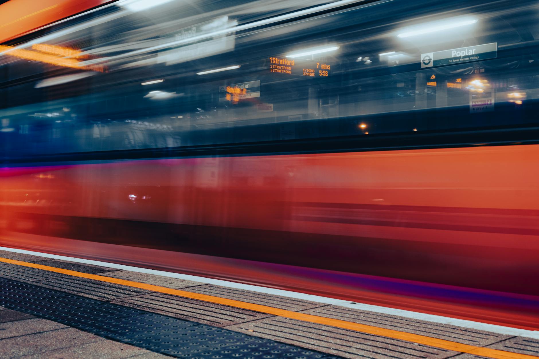 Blurred motion of a train speeding through a London station at night.